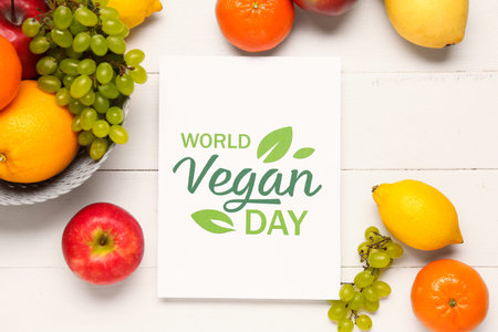 Card with text WORLD VEGAN DAY and basket of fresh fruits on white wooden backgroundの写真素材