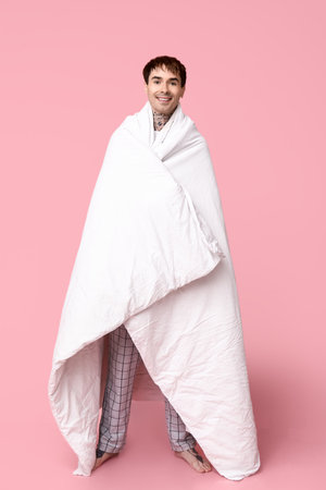 Tattooed young man in pajamas on pink backgroundの写真素材