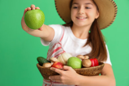Little farmer with fresh food on green background, closeupの写真素材