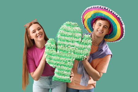 Young couple with Mexican pinata on green background