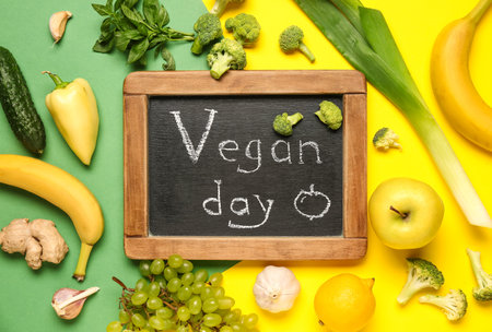Chalkboard with the word VEGAN DAY, fresh vegetables and fruits on color backgroundの写真素材