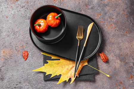 Stylish autumn table setting with maple leaf and pumpkins on gray grunge backgroundの写真素材