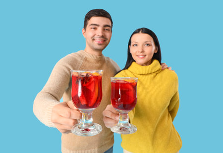 Young couple with glasses of mulled wine on blue backgroundの写真素材