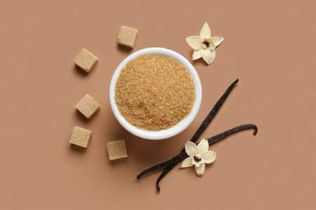 Bowl with aromatic vanilla sugar, flowers and sticks on brown backgroundの写真素材