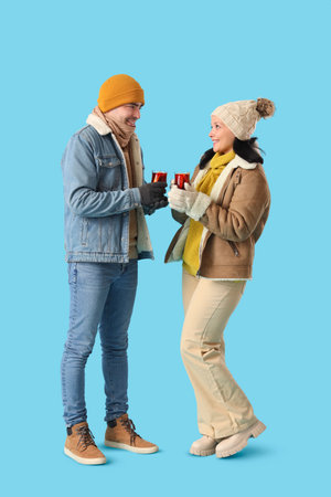 Young couple with glasses of mulled wine on blue backgroundの写真素材