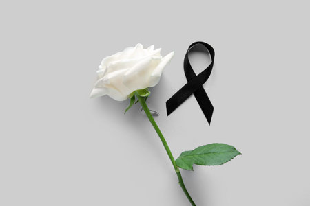 Beautiful rose flower and black funeral ribbon on gray backgroundの写真素材