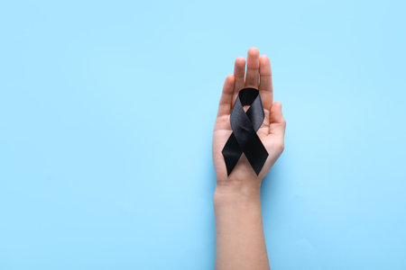 Woman holding black funeral ribbon on blue backgroundの写真素材