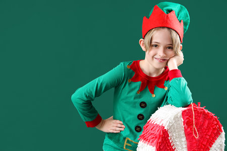 Cute little boy in elf costume with candy cane pinata on green backgroundの写真素材