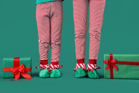 Cute little children in elves costumes with Christmas gift boxes on green background, closeupの写真素材