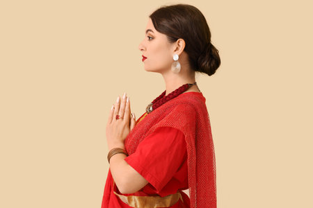 Beautiful young Indian woman in sari on beige background