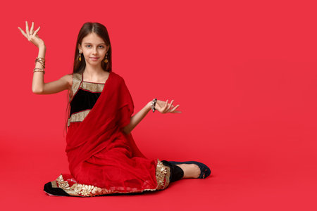 Cute little Indian girl in sari on red background. Divaly celebrationの写真素材