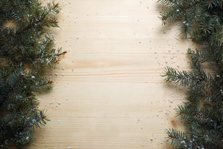 Beautiful Christmas tree branches with snow on beige wooden background