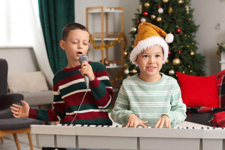 Cute little boys playing synthesizer and singing at home on Christmas Eveの写真素材