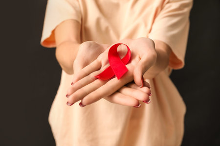Woman with red ribbon on black background. World AIDS Day concept