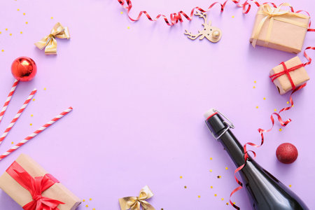 Frame made of champagne with Christmas decorations and gift boxes on lilac backgroundの写真素材