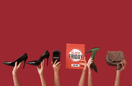 Female hands holding poster with text BLACK FRIDAY, payment terminal and women accessories on red backgroundの写真素材
