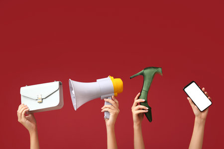 Female hands with megaphone, mobile phone and women accessories on red background. Black Friday saleの写真素材
