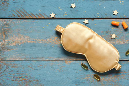Composition with sleep mask, earplugs and pills on color wooden backgroundの写真素材