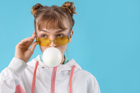 Sporty young woman with chewing gum on blue background, closeupの写真素材