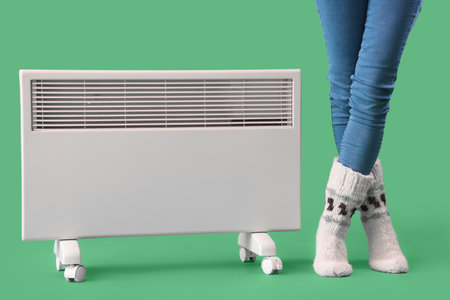 Young woman with radiator on green backgroundの写真素材