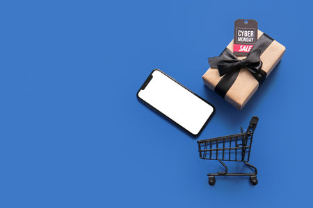 Modern mobile phone, gift box and shopping card on color background. Cyber Monday saleの写真素材