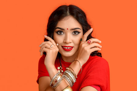 Beautiful happy Indian woman in sari on orange background