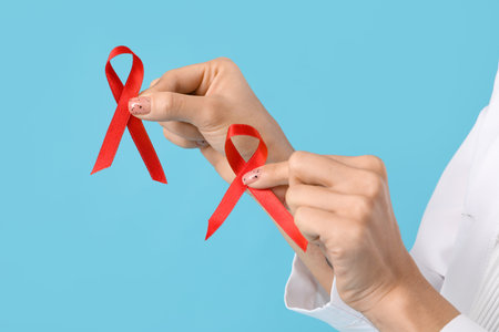 Female doctor with red ribbons on blue background, closeup. World AIDS Day concept