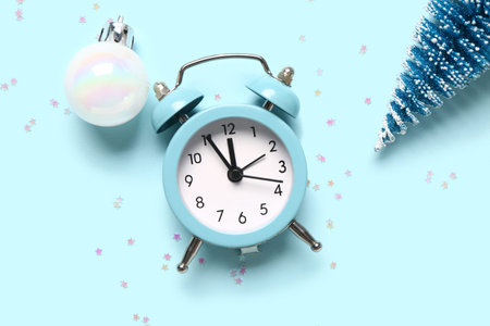 Alarm clock with Christmas ball and fir tree on blue background