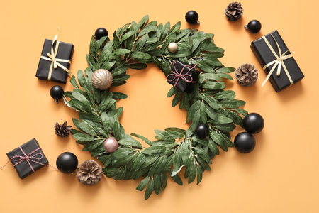 Christmas mistletoe wreath with balls, cones and gift boxes on orange backgroundの写真素材