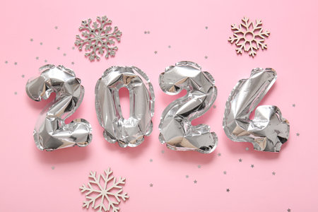 Figure 2024 made of foil balloons with snowflakes and confetti on pink backgroundの写真素材