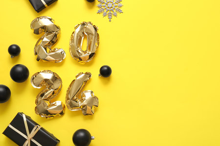 Figure 2024 made of foil balloons with Christmas balls and gift box on yellow backgroundの写真素材