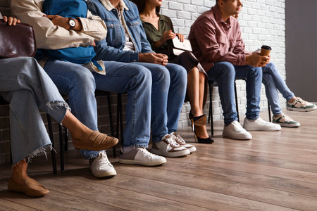 People waiting for their turn near gray brick wall