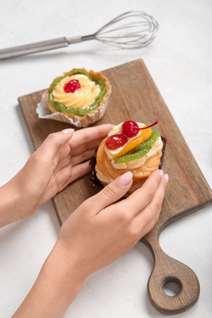 Female confectioner with tasty cakes on white backgroundの写真素材