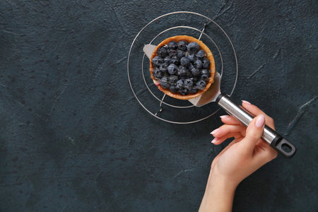 Female confectioner with tasty cake on black backgroundの写真素材