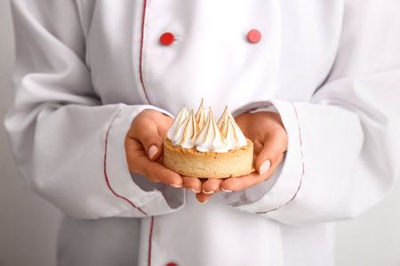 Female confectioner with tasty cake on white backgroundの写真素材