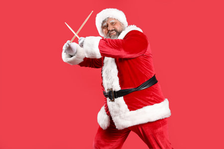 Cool Santa Claus with drumsticks on red backgroundの写真素材