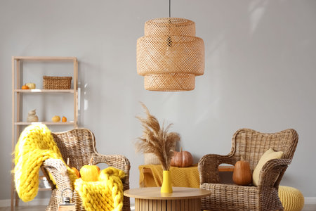 Autumn interior of living room with wicker armchairs, pumpkins and pampas grass on coffee tableの写真素材