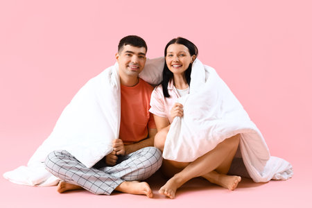 Young couple with blanket on pink backgroundの写真素材