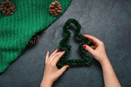 Female hands with red manicure and Christmas decoration on black grunge backgroundの写真素材