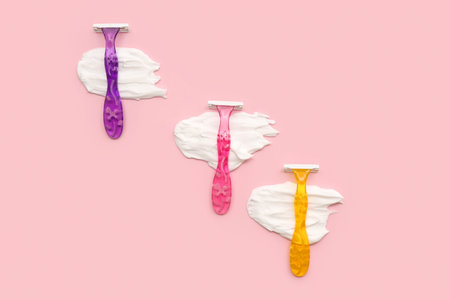 Safety razors and shaving foam on pink background