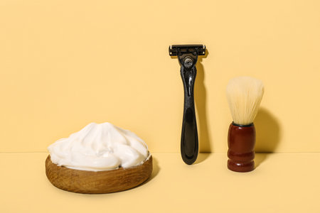 Safety razor with brush and bowl of shaving foam on orange backgroundの写真素材