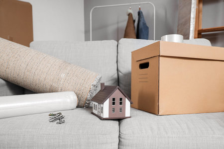 House model with keys and moving box on sofa in living room