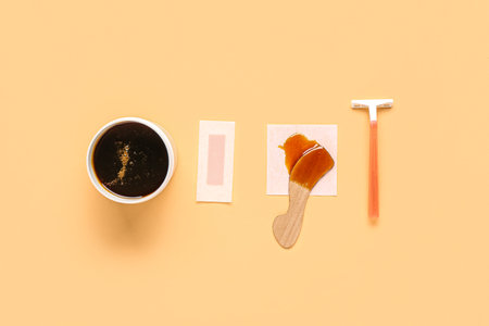 Safety razor, wax strip, jar and spatula with sugaring paste on orange backgroundの写真素材