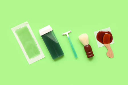 Safety razor with liposoluble wax cartridge, strip and brush on green backgroundの写真素材