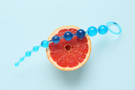 Anal plug from sex shop and half of tasty grapefruit on blue backgroundの写真素材
