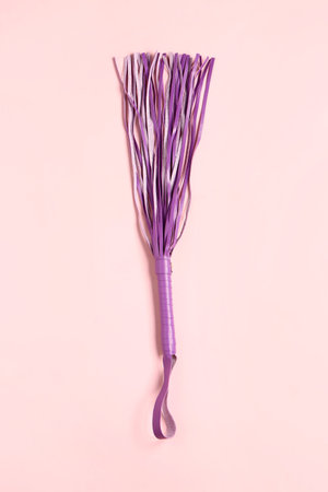 Purple whip from sex shop on pink background