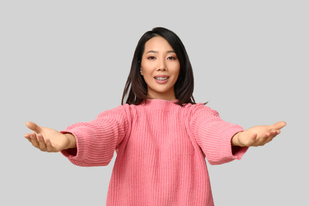 Young Asian woman opening arms for hug on light backgroundの写真素材