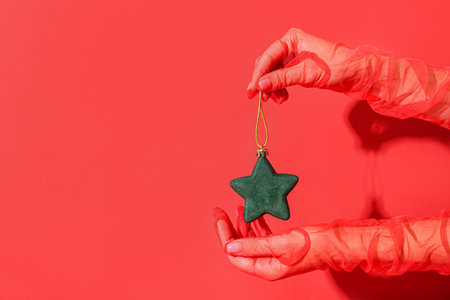 Female hands with Christmas ball on red backgroundの写真素材