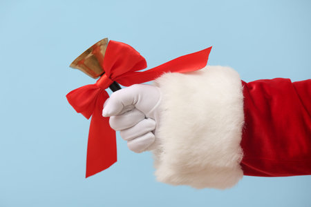 Santa Claus holding Christmas bell with red bow on blue backgroundの写真素材