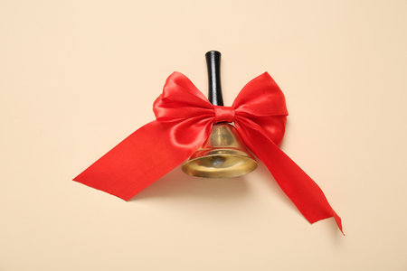 Christmas bell with red bow on beige backgroundの写真素材